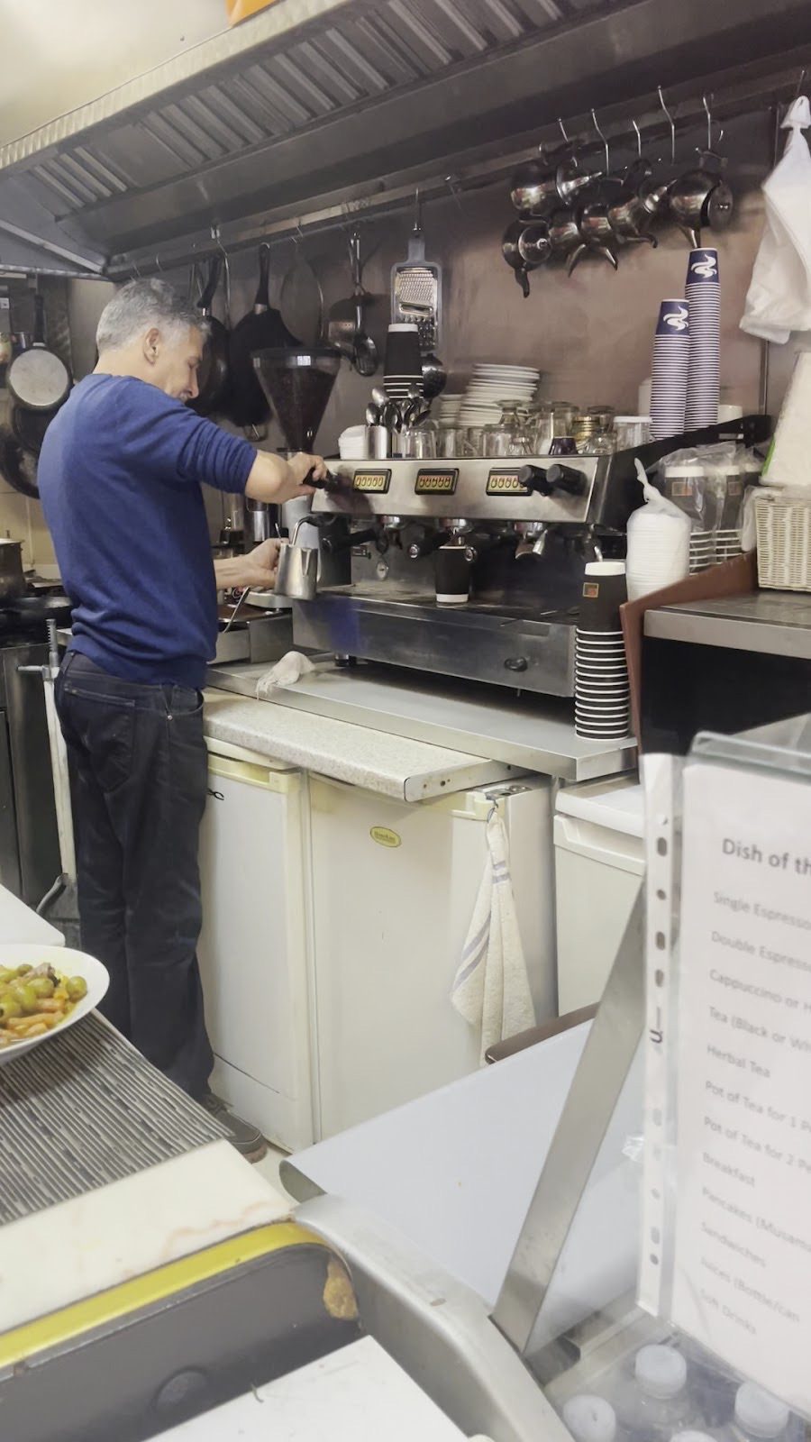 A member of staff making coffee at the espresso machine behind the counter